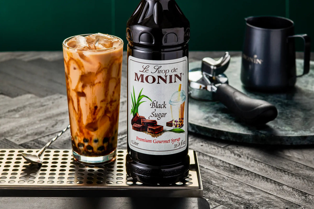 Monin Black Sugar Syrup bottle beside an iced black sugar bubble tea