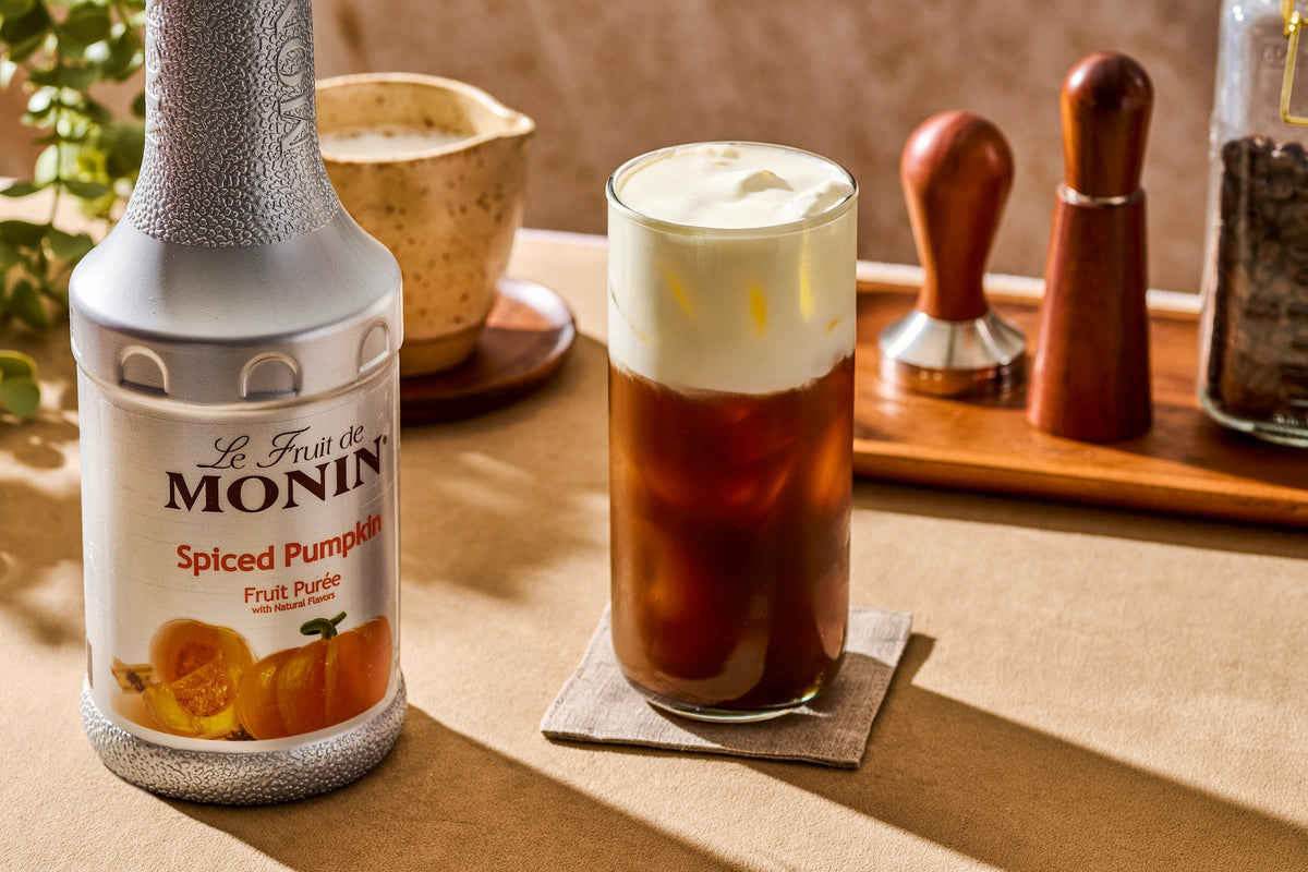 Monin Spiced Pumpkin Purée paired with an iced fall coffee topped with creamy cold foam, highlighting rich pumpkin flavour for seasonal beverages.
