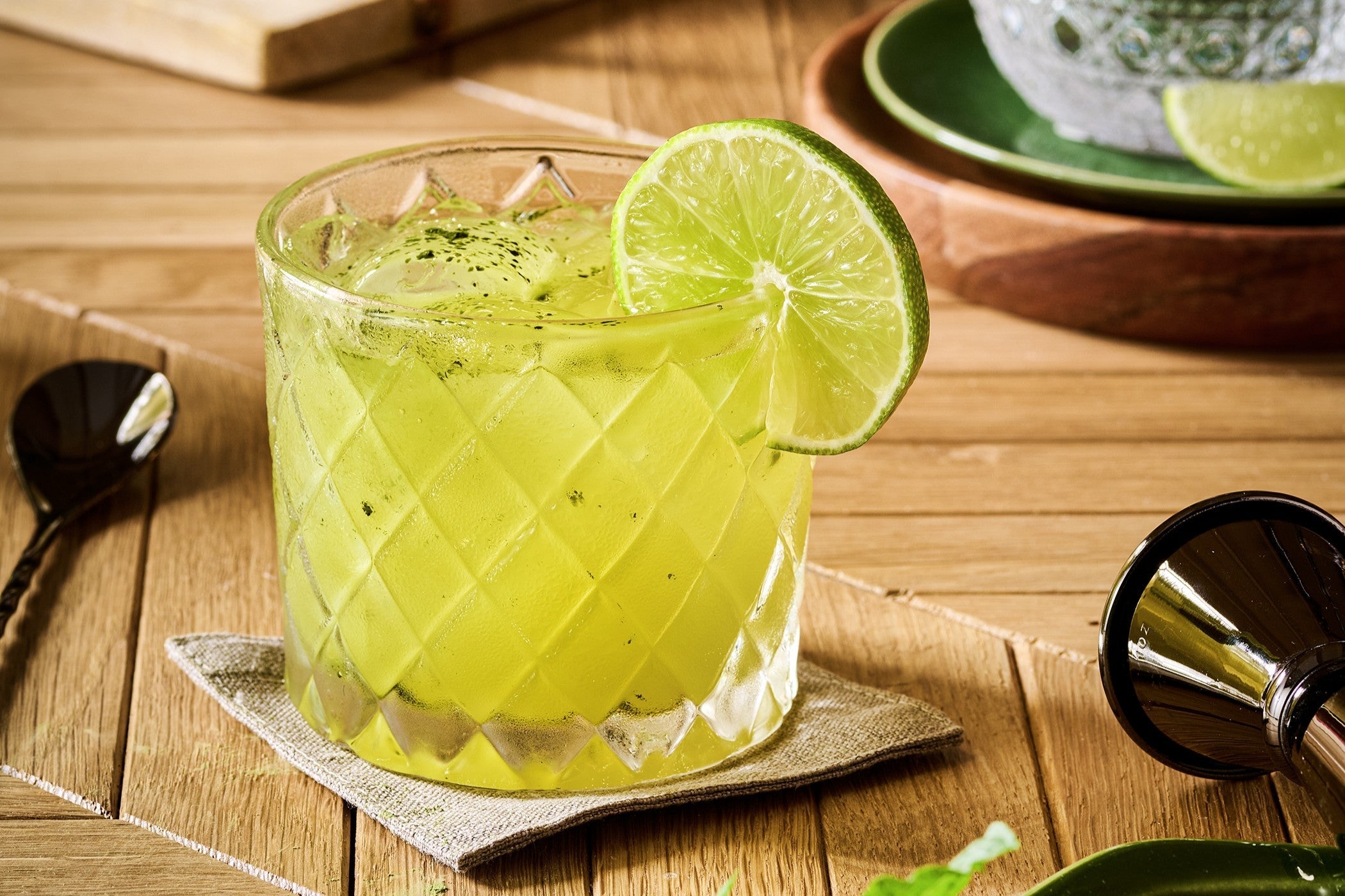 Bright green lime-mint mocktail in a faceted rocks glass with crushed ice and a fresh lime wheel.