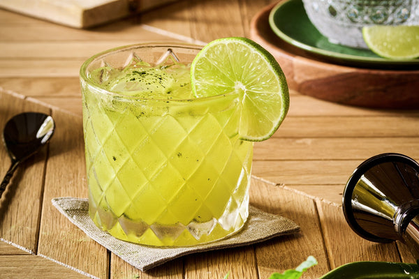 Bright green lime-mint mocktail in a faceted rocks glass with crushed ice and a fresh lime wheel.