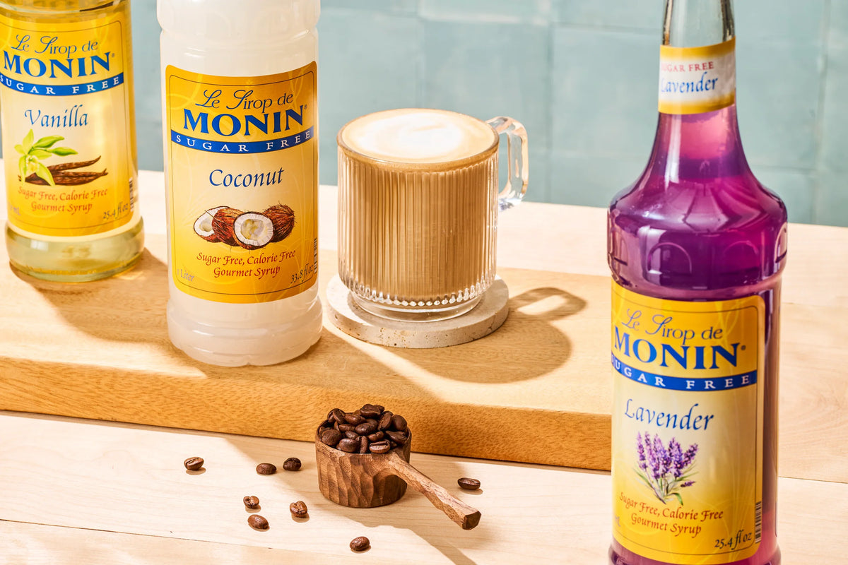 Monin Sugar Free Vanilla, Coconut and Lavender Syrups with a creamy coffee drink and coffee beans