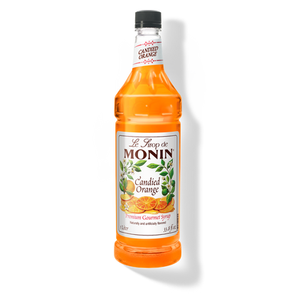A 1L-bottle of Monin Candied Orange Syrup with a label showing an orange slice and green leaves, indicating the flavor of the syrup.