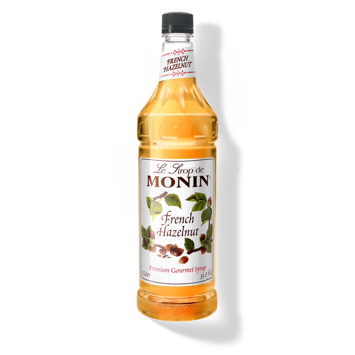 A bottle of Monin French Hazelnut Syrup with a label showing the brand name and the flavor, placed against a white background.
