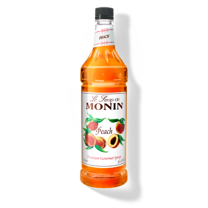 A 1L bottle of Monin Peach Syrup showing the brand name and flavour, placed against a white background
