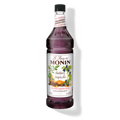 A bottle of Monin Blackberry Sangria Mix with a label showing a picture of blackberries and text indicating the flavor.