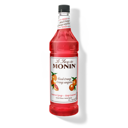A bottle of Monin Blood Orange Syrup with a label showing an image of a blood orange. The bottle is transparent, showing the bright red syrup inside.