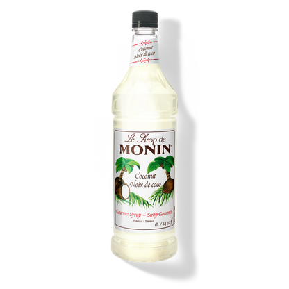 A bottle of Monin Coconut Syrup (Noéx de coco) with a black cap, featuring a white label with green palm leaves and coconuts.