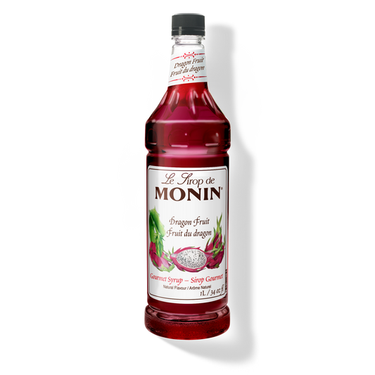 A bottle of Monin Dragon Fruit syrup, featuring a black cap, white label with red dragon fruit illustrations, and a vibrant red liquid inside, set against a plain white background with a soft shadow.