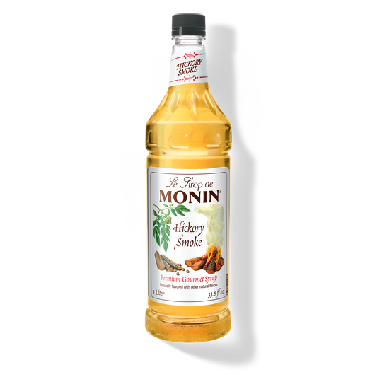 A 1L-bottle of Monin Hickory Smoke Syrup with a label showing the brand name and the flavor, placed against a white background.
