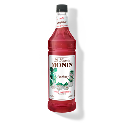 A bottle of Monin Pineberry Syrup with a label showing the brand name and the flavor, placed against a white background.
