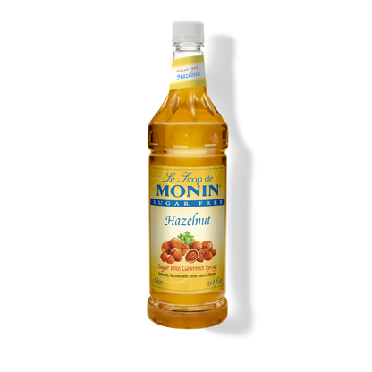 A bottle of Monin Sugar Free Hazelnut Syrup, with a yellow label displaying the product name and an image of hazelnuts.