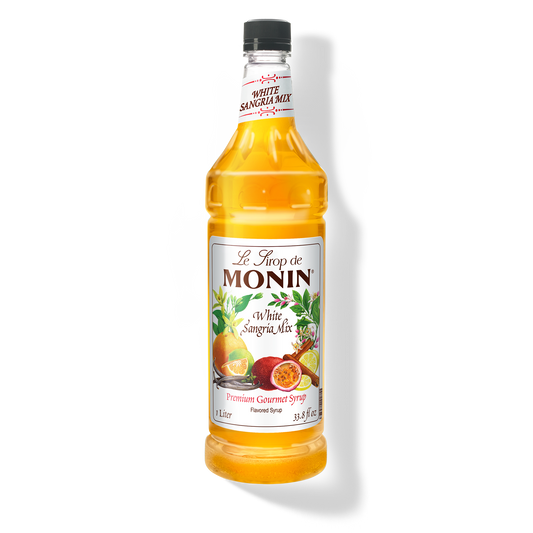 A bottle of Monin White Sangria Mix Syrup with a label showing the brand name and the flavor, placed against a white background.

