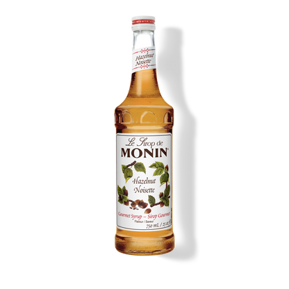 A 750mL-bottle of Monin Hazelnut Syrup with a label showing the brand name and the flavor, placed against a white background.