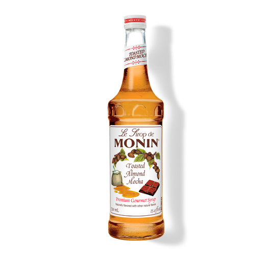 A bottle of Monin Toasted Almond Mocha Syrup with a label showing the brand name and the flavor, placed against a white background.
