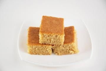 Three pieces of Brown Butter Toffee Blondies stacked on a white plate with a white background