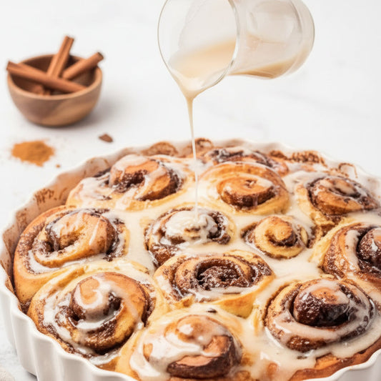 Freshly baked cinnamon rolls drizzled with Maple Bourbon Cream Sauce, showcasing a warm breakfast pastry made with Monin Maple Spice Syrup 