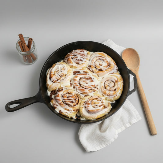 Freshly baked cinnamon rolls made with Monin Maple Spice Syrup, topped with creamy icing and served warm in a cast iron skillet for a cozy fall breakfast or brunch.