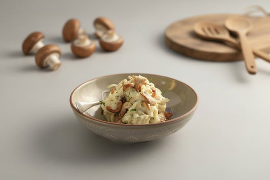 Bowl of mashed potatoes with mushrooms on a light surface