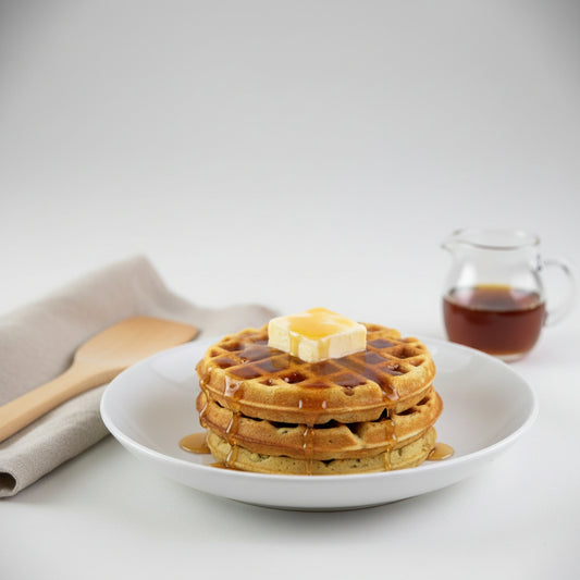 Pumpkin spice waffles made with Monin Spiced Pumpkin Purée, topped with butter and maple syrup for a warm fall breakfast.
