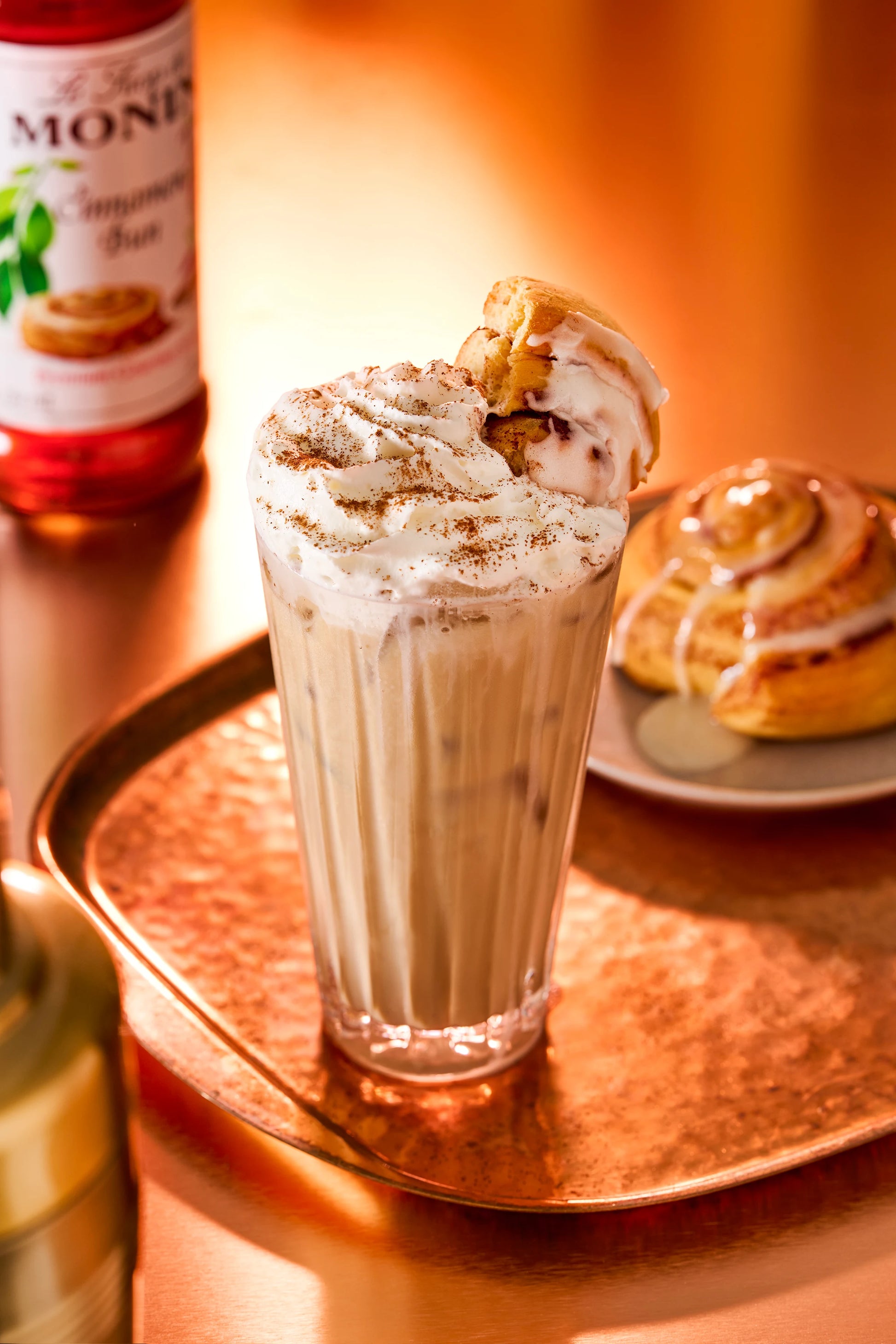 Monin Cinnamon Bun Syrup with a creamy cinnamon bun milkshake topped with whipped cream, cinnamon and a cinnamon roll for a sweet dessert drink.