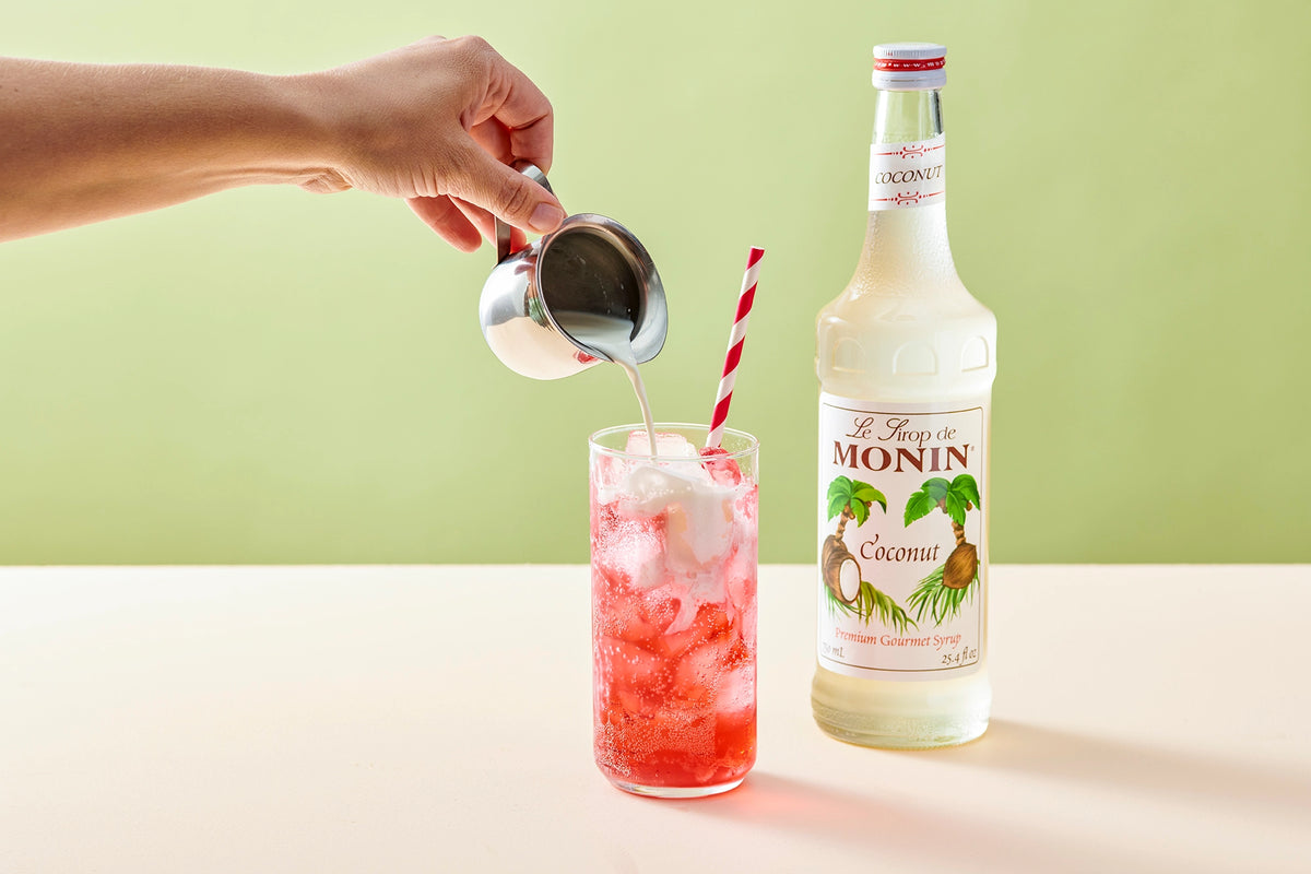 Monin Coconut Syrup with a pink coconut soda topped with cream