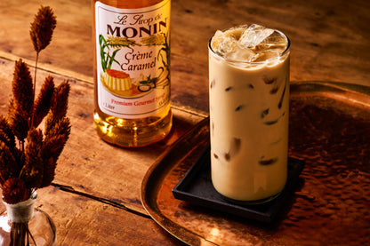 Monin Crème Caramel Syrup with iced caramel coffee on a tray