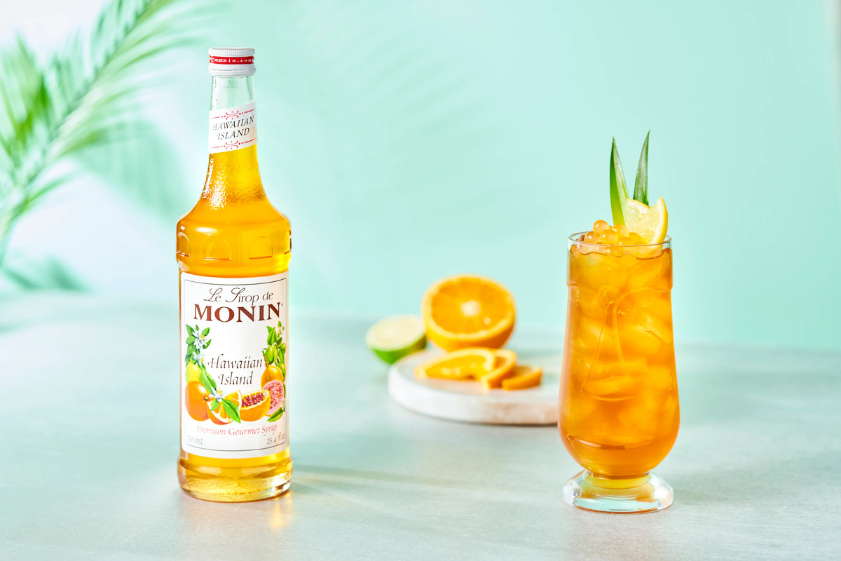 Monin Hawaiian Island Syrup with tropical iced drink, citrus slices and island-inspired garnish