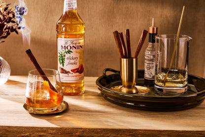 Monin Hickory Smoke Syrup with smoky bourbon cocktail, orange peel and cinnamon stick
