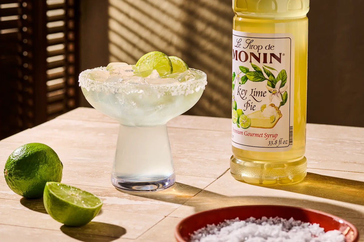 Monin Key Lime Pie Syrup with key lime cocktail, lime slices and salted rim.