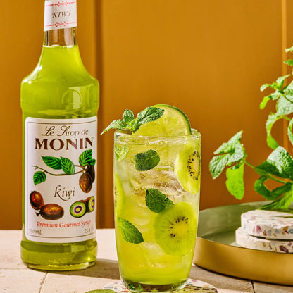 Monin Kiwi Syrup with an iced kiwi drink and fresh sliced kiwis