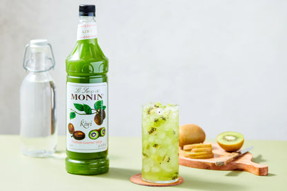 Monin Kiwi Syrup with an iced kiwi drink and fresh sliced kiwis