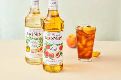 Monin Peach Syrup with a refreshing peach beverage, highlighting juicy peach flavour for cocktails, lemonades and iced drinks.