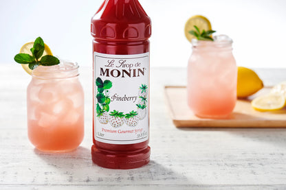 Monin Pineberry Syrup with two pink pineberry lemonades, lemon slices and mint garnish