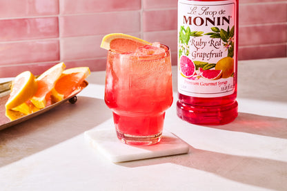 Monin Ruby Red Grapefruit Syrup with a sparkling grapefruit drink garnished with fresh grapefruit