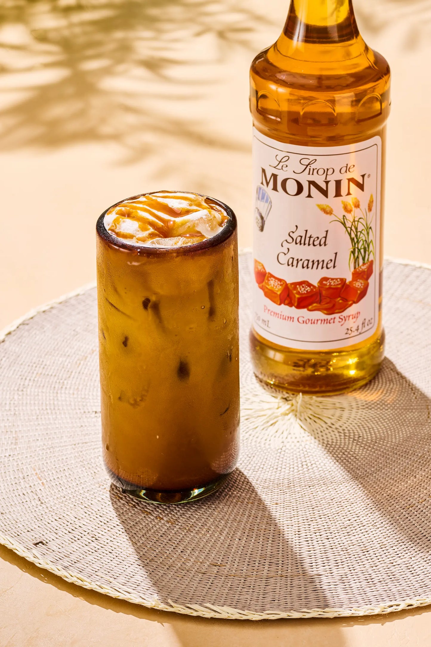 Monin Salted Caramel Syrup bottle beside an iced salted caramel latte