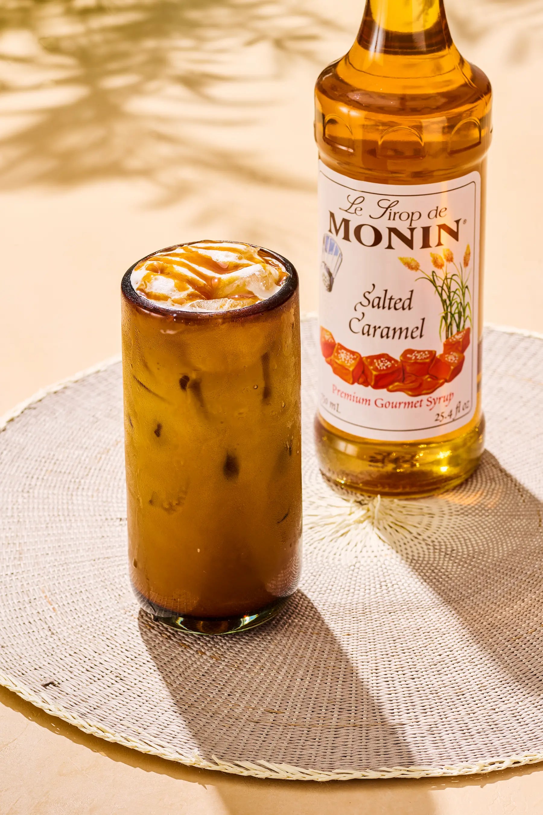 Monin Salted Caramel Syrup bottle beside an iced salted caramel latte