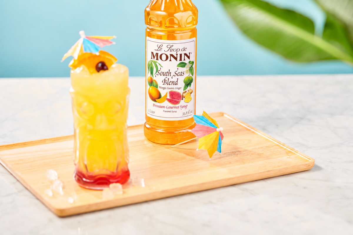 Monin South Seas Blend Syrup with tropical tiki drink, citrus garnish and cocktail umbrella