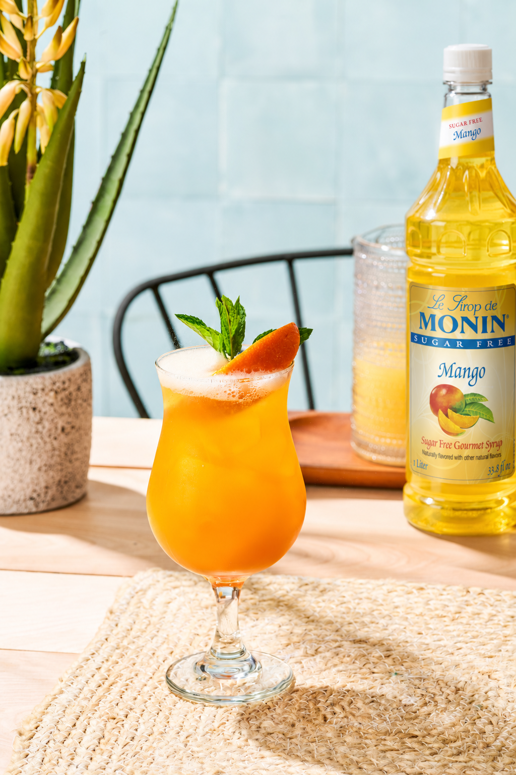 Monin Sugar Free Mango Syrup with a tropical mango mocktail and fresh mango garnish