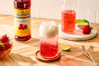 Monin Sugar Free Strawberry Syrup with a sparkling strawberry drink, cream topping and fresh strawberries