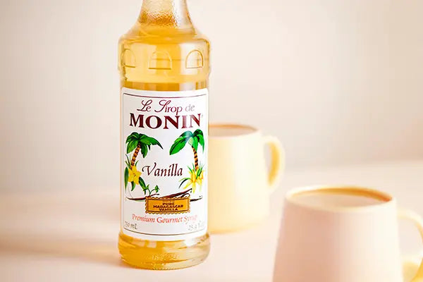 Monin Vanilla Syrup bottle beside freshly brewed coffee